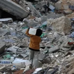 Saat ini jutaan anak masih menghadapi masalah-masalah yang sering membuat mereka merasa terancam hingga menimbulkan rasa takut. Tampak dalam foto, seorang anak laki-laki Palestina membawa sebuah wadah plastik saat dia berjalan melewati puing-puing di samping sebuah bangunan yang hancur akibat pemboman Israel baru-baru ini di Khan Yunis di Jalur Gaza selatan pada 19 November 2024.